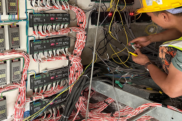 An electrician installing a DMX lighting controller and power supply
